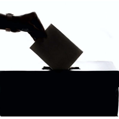 image of a hand putting a ballot into a box